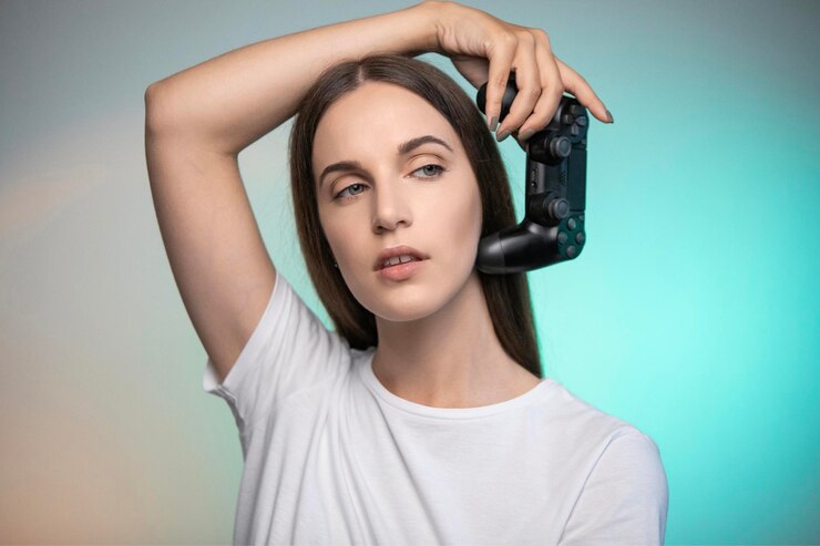Hermosa mujer sosteniendo el controlador de la consola en colores de fondo. Persona adulta joven disfrutando