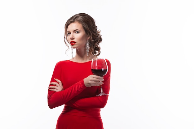 Hermosa mujer sosteniendo una copa de vino en el espacio blanco