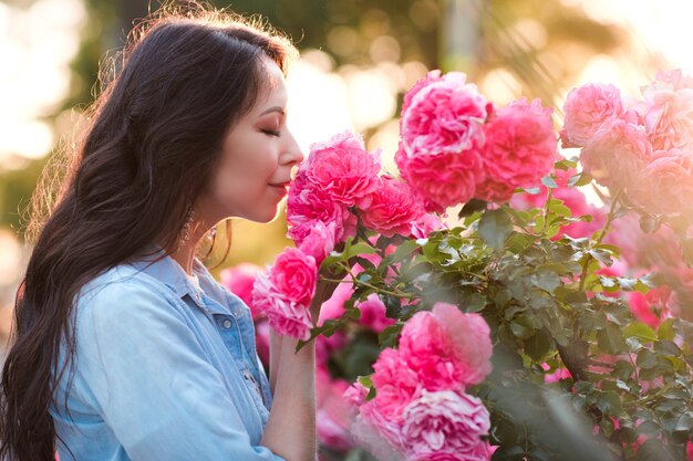 Foto hermosa mujer sosteniendo flores color de rosa rosa en el jardín