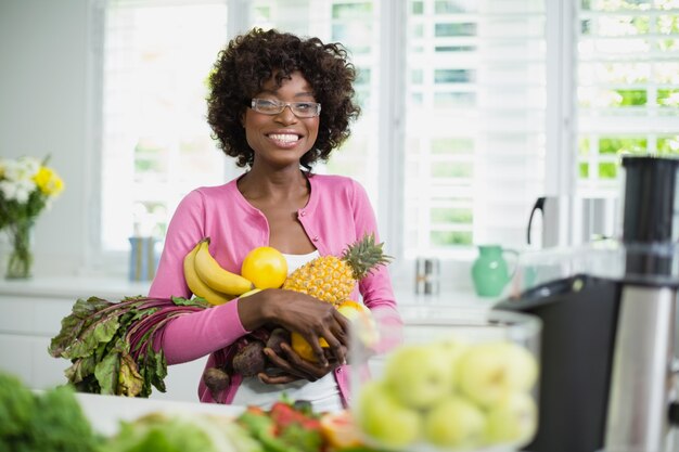 Hermosa mujer sosteniendo frutas en casa