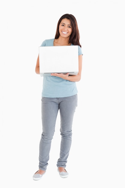 Hermosa mujer sosteniendo una laptop mientras posando