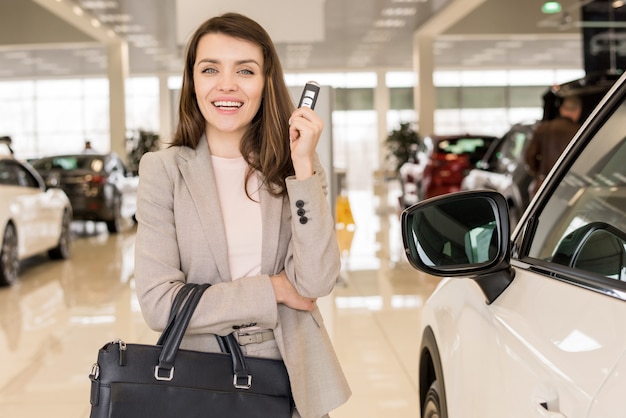 Hermosa mujer sosteniendo las llaves del auto en la sala de exposiciones