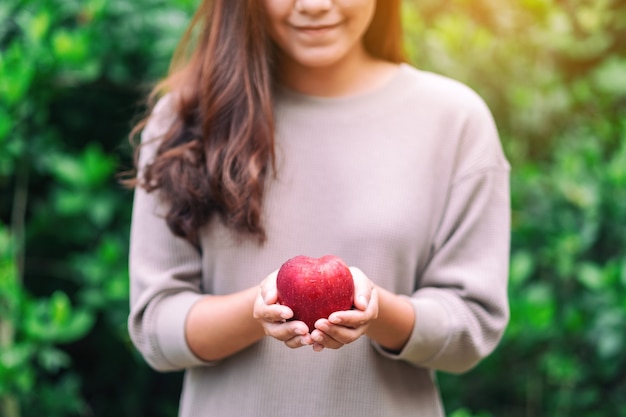 Una hermosa mujer sosteniendo una manzana roja fresca en la mano