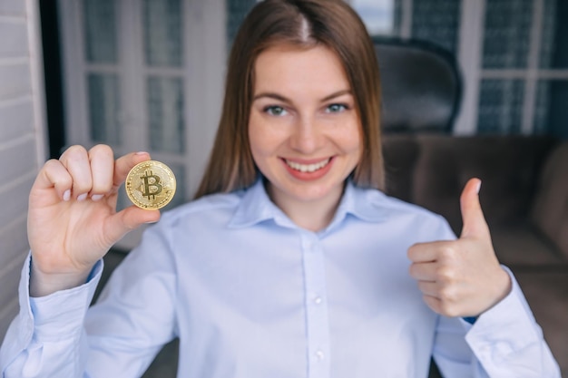 Hermosa mujer sosteniendo nueva criptomoneda bitcoin levanta el pulgar