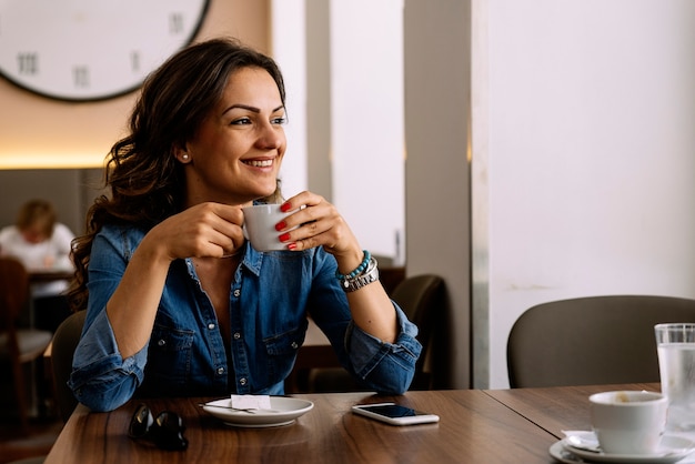 Hermosa mujer sosteniendo una taza de café en la cafetería.
