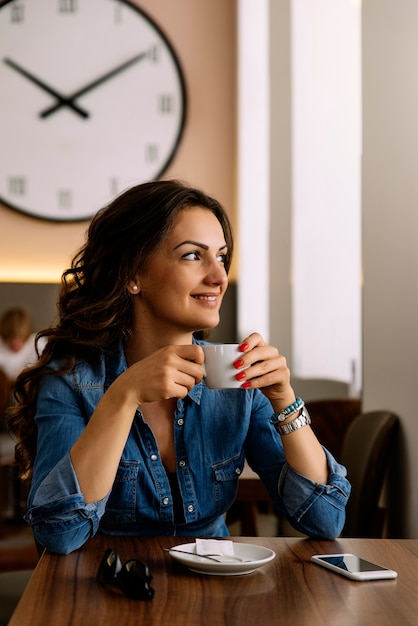 Foto hermosa mujer sosteniendo una taza de café en la cafetería.