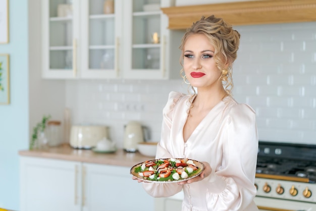 Hermosa mujer sostiene en su plato de mano con ensalada de frutas queso fresa roja