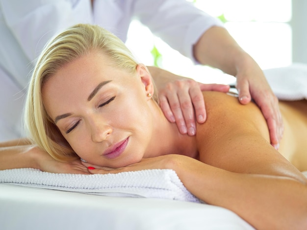 Hermosa mujer spa acostada sobre una toalla en el salón de spa