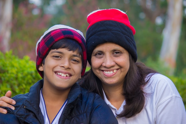 Hermosa mujer y su pequeño y lindo hijo con gorros de invierno sonriendo a la cámara