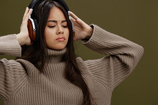 Hermosa mujer en un suéter escuchando música con auriculares estilo de vida divertido