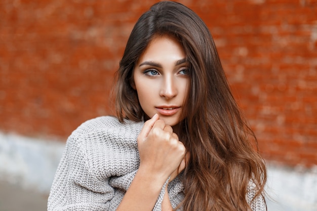 Hermosa mujer en un suéter gris escondido