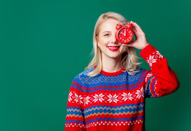 Hermosa mujer en suéter de Navidad con reloj despertador