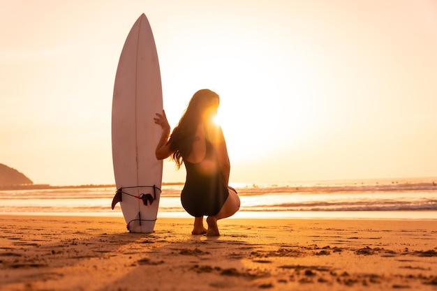 Hermosa mujer surfista en la playa al atardecer Bali Indonesia