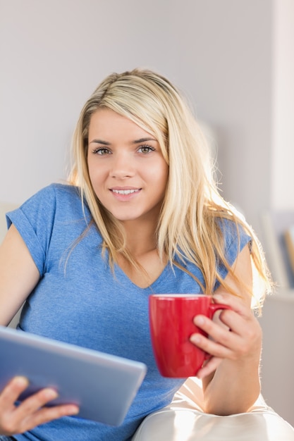 Hermosa mujer con tableta digital mientras bebe café en casa