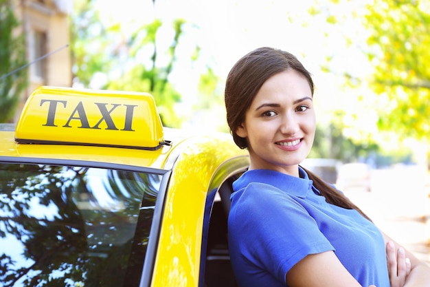 Hermosa mujer taxista de pie cerca del coche