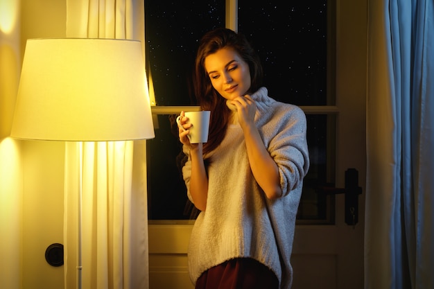 Hermosa mujer con una taza de bebida caliente