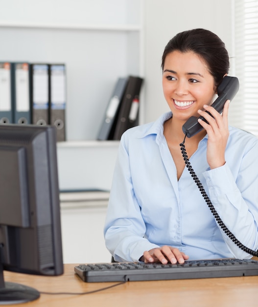 Hermosa mujer en el teléfono mientras se escribe en un teclado