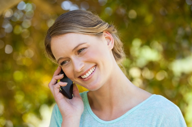 Hermosa mujer con teléfono móvil en el parque