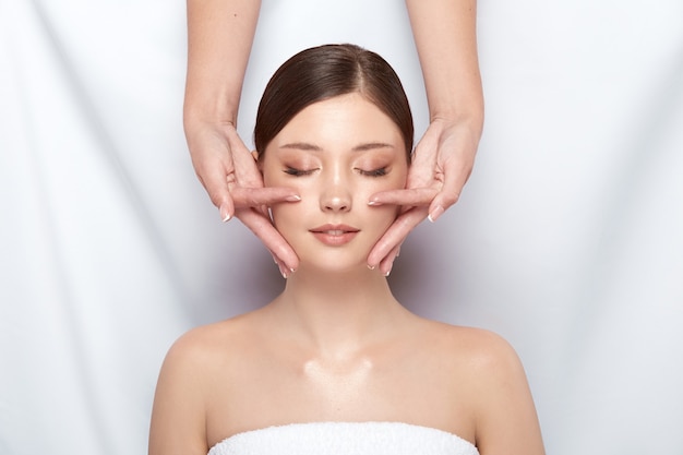 Hermosa mujer con terapia facial con esteticista en blanco