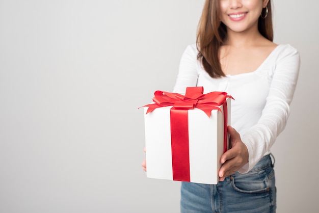 Hermosa mujer tiene caja de regalo en la pared blanca