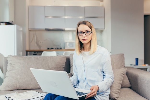 Hermosa mujer tiene consulta en línea usando laptop sentado en el sofá en casa