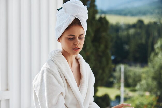 Foto hermosa mujer con una toalla en la cabeza en un albornoz blanco alojándose en el balcón de un hotel estilo de vida foto de alta calidad