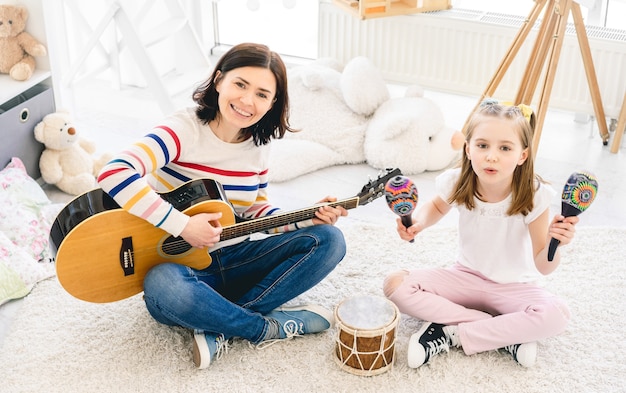 Hermosa mujer tocando la guitarra y cantando con niña linda