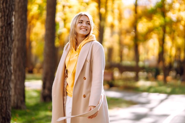 Hermosa mujer toma fotos con cámara retro en el bosque de otoño Niña sonriente disfrutando del clima otoñal