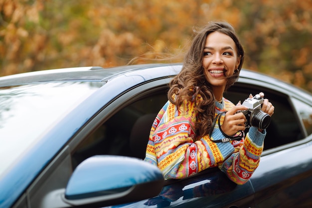 Hermosa mujer toma fotos en la cámara desde la ventana del auto Concepto de estilo de vida de relajación de descanso