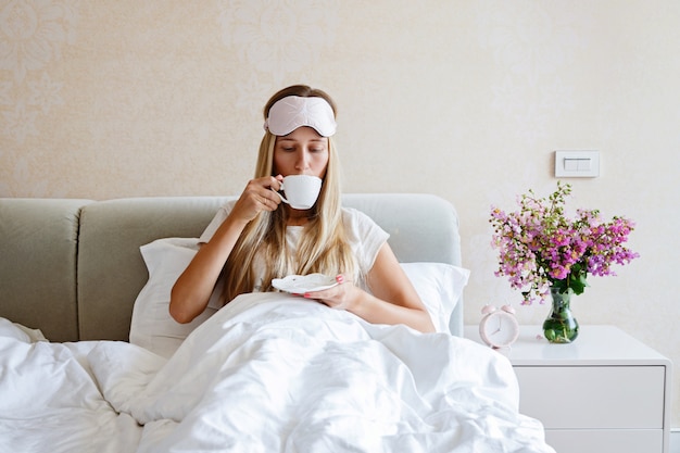 Hermosa mujer tomando café en la cama