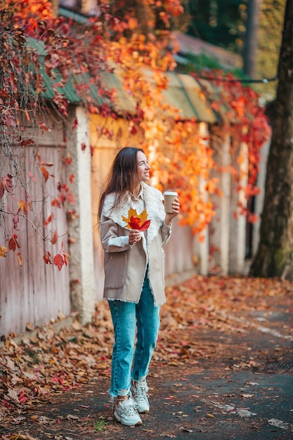 Hermosa mujer tomando café en el parque otoño bajo el follaje de otoño