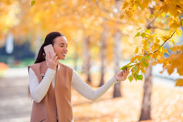 Hermosa mujer tomando café en el parque de otoño bajo el follaje de otoño