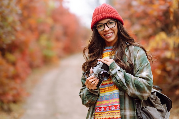 Hermosa mujer tomando fotos en el bosque de otoño Mujer sonriente disfrutando del clima otoñal Estilo de vida