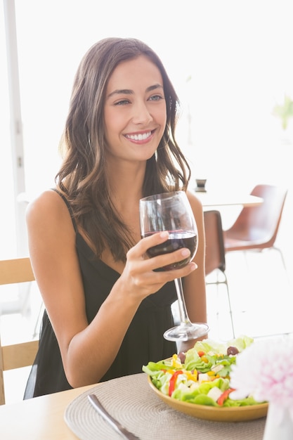 Hermosa mujer tomando vino con comida
