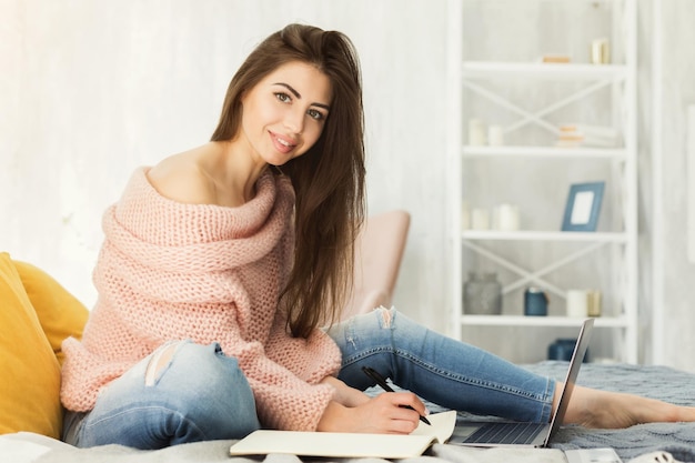 Hermosa mujer trabajando cómodamente en casa con una laptop