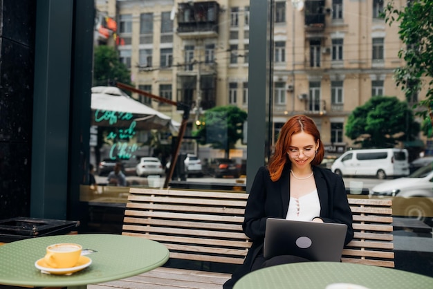 Hermosa mujer trabajando en una laptop en un café al aire libre