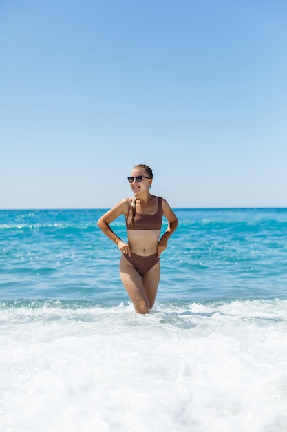 Hermosa mujer en traje de baño y camina sobre la arena de la playa en Turquía. Vacaciones en turquía. Fotografiado con el mar y las olas de fondo. Enfoque selectivo