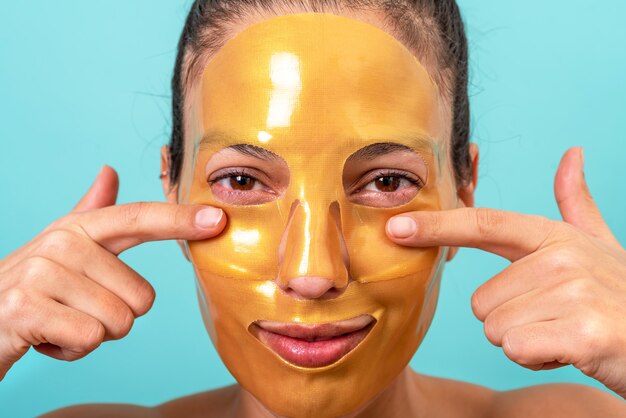 Hermosa mujer con tratamiento de mascarilla facial de gel de colágeno para el cuidado de la piel