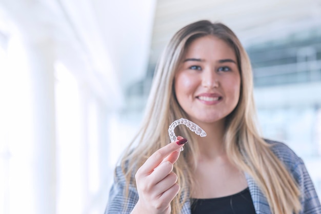 Foto hermosa mujer turca rubia está sosteniendo un espacio de copia invisaligner incluye