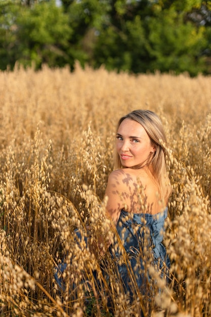 Hermosa mujer ucraniana con un vestido azul en un campo de trigo amarillo