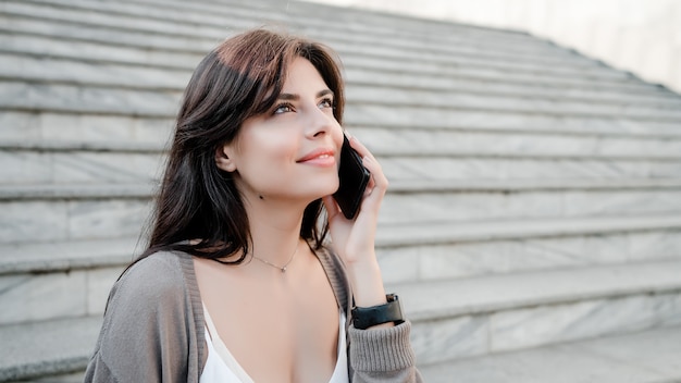 Hermosa mujer usando el teléfono al aire libre en el parque de la ciudad