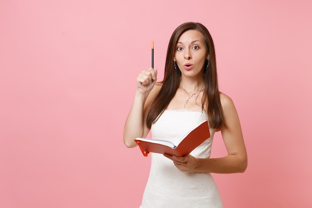 Hermosa mujer vestida de blanco tiene una nueva idea, escribiendo notas en el diario, cuaderno