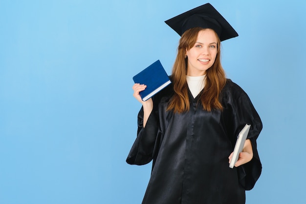 Hermosa mujer vestida con gorro de graduación y bata de ceremonia con grado de aspecto positivo y feliz de pie y sonriendo con una sonrisa segura