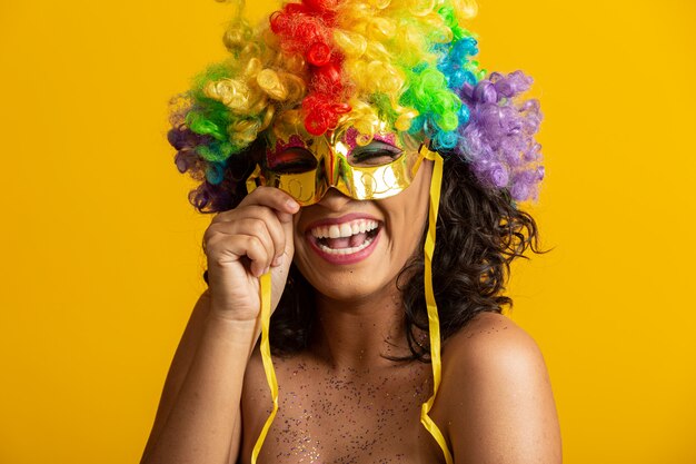 Hermosa mujer vestida para la noche de carnaval. Mujer sonriente lista para disfrutar del carnaval con una colorida peluca y máscara