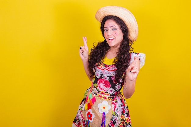 Hermosa mujer vestida con ropa típica para una Festa Junina Crucemos los dedos torciendo deseando