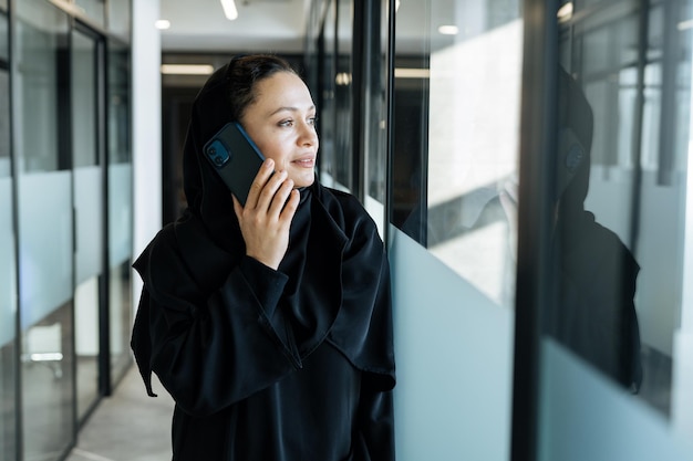 Hermosa mujer con vestido abaya trabajando e imprimiendo documentos. Empleada de mediana edad en el trabajo en una oficina comercial en Dubai. Concepto sobre las culturas y el estilo de vida de Oriente Medio