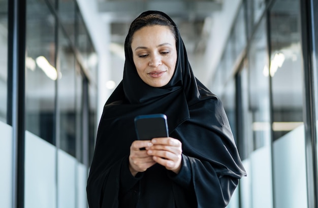 Hermosa mujer con vestido abaya trabajando e imprimiendo documentos. Empleada de mediana edad en el trabajo en una oficina comercial en Dubai. Concepto sobre las culturas y el estilo de vida de Oriente Medio