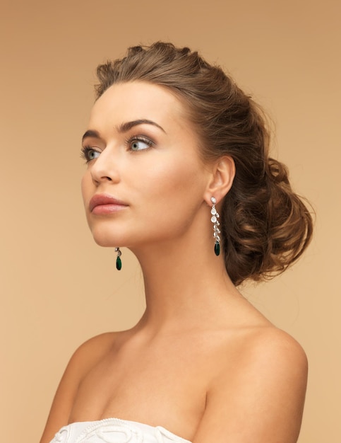 Foto hermosa mujer en vestido blanco y aretes de diamantes