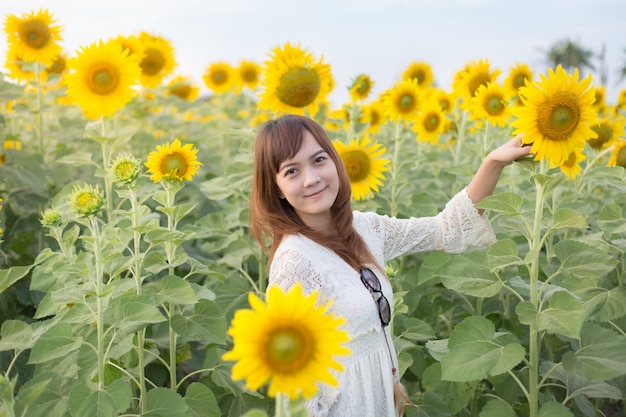 Hermosa mujer con un vestido blanco en un campo de girasoles de verano