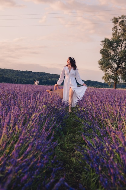 Foto hermosa mujer en vestido blanco en el campo de lavanda al atardecer